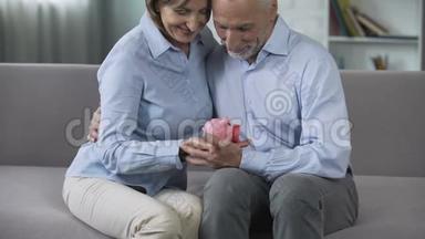 退休夫妇在沙发上拿着储蓄罐，成熟后交了保险，有保障